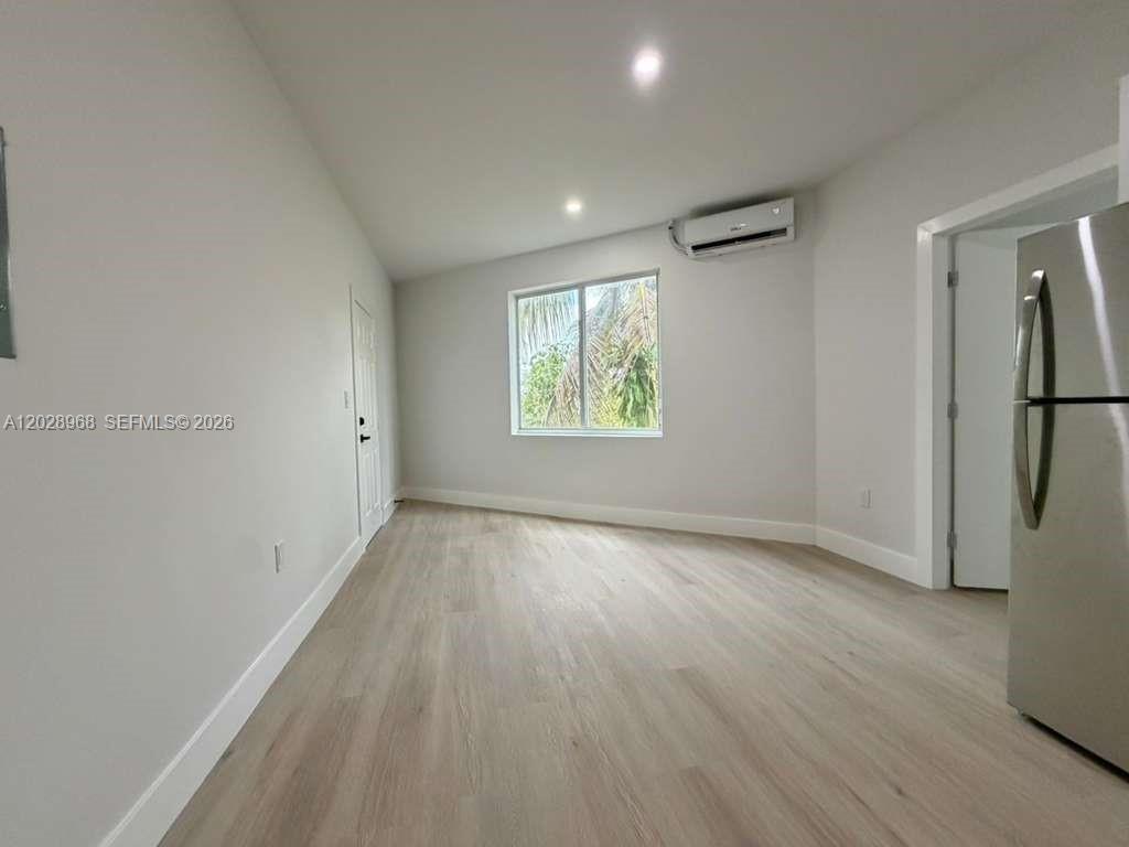 A room with light wood-look flooring, a window, and a wall-mounted air conditioning unit — 2425 SW 6th St # 6, Miami FL 33135, MIAMI, FL