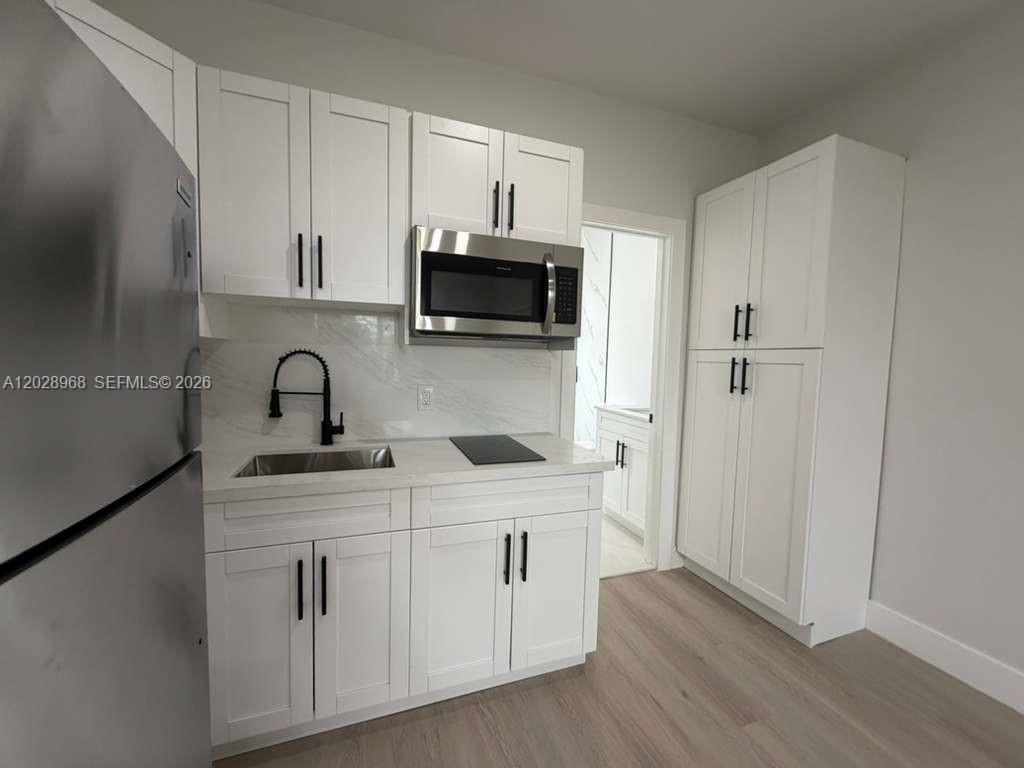 A small kitchen features white shaker cabinets, stainless steel appliances, and light wood-look flooring — 2425 SW 6th St # 6, Miami FL 33135, MIAMI, FL