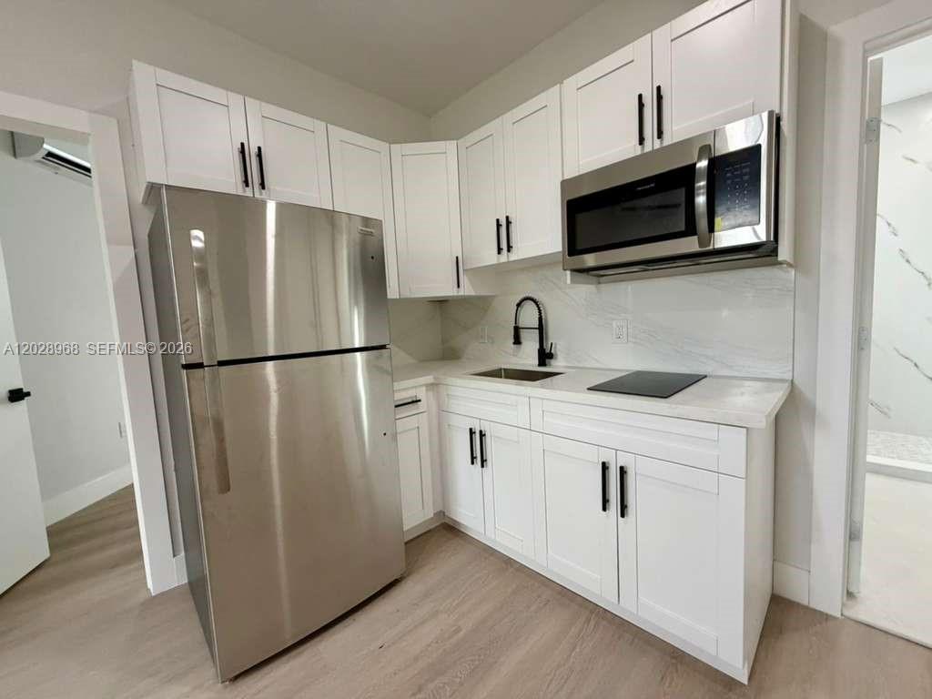 A small kitchen features white cabinets, stainless steel appliances, and light wood-look flooring — 2425 SW 6th St # 6, Miami FL 33135, MIAMI, FL