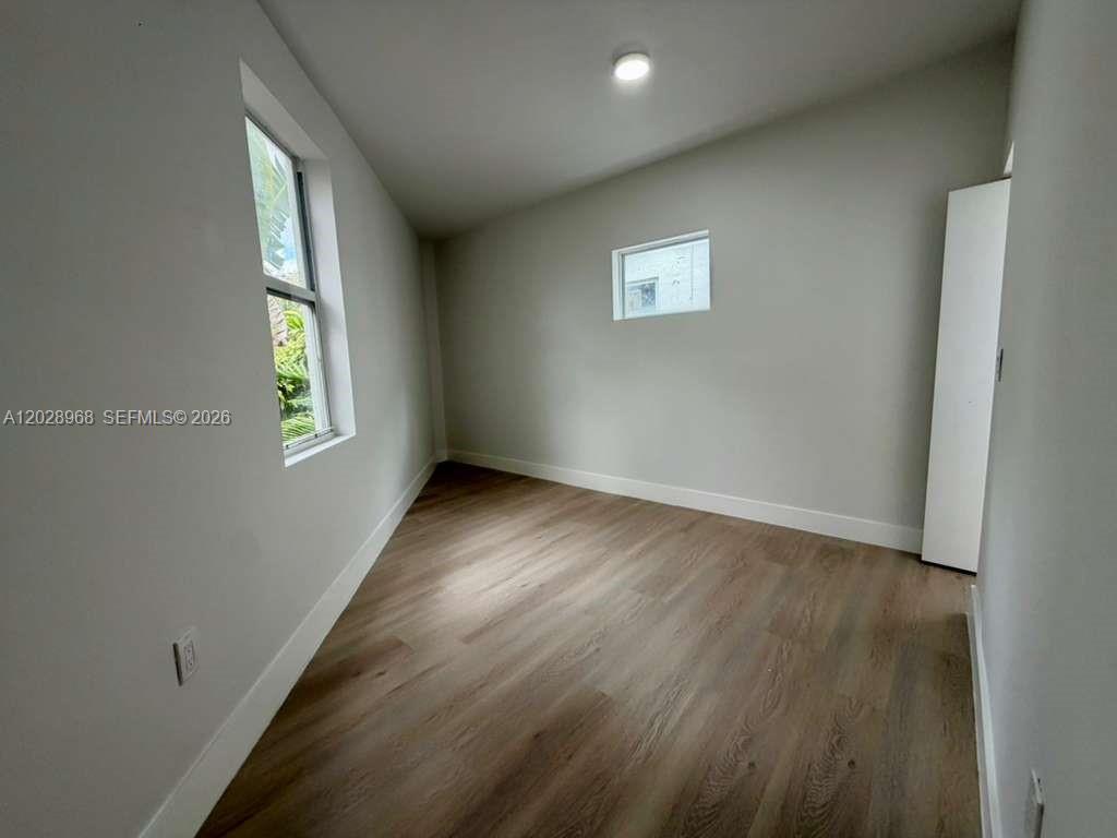 An empty room features light wood-look flooring, white walls, two windows, and a ceiling light — 2425 SW 6th St # 6, Miami FL 33135, MIAMI, FL