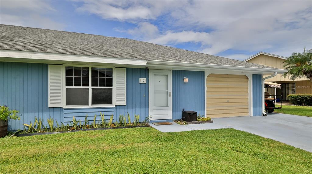A blue single-story house features a white front door, a garage, and a front lawn — 12 BOGEY CIRCLE, NEW SMYRNA BEACH, FL