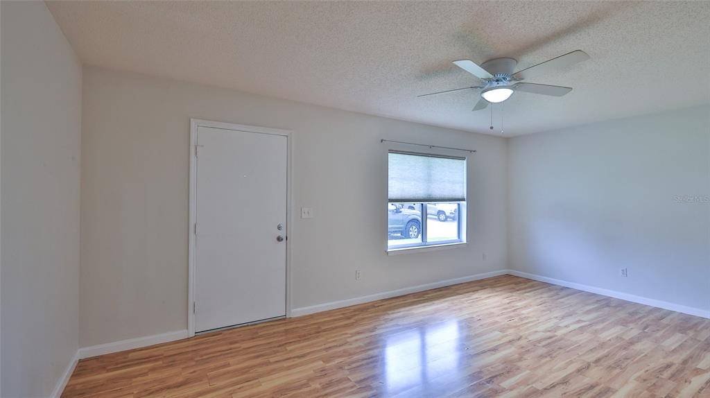 An empty room features light-colored walls, wood-look flooring, a ceiling fan, and a window — 12 BOGEY CIRCLE, NEW SMYRNA BEACH, FL