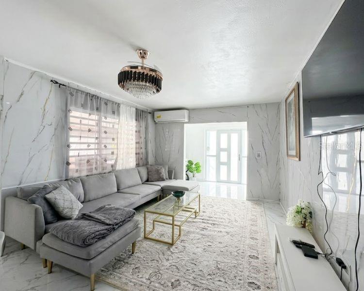 A living room features a gray sectional sofa, a glass coffee table, and marble-patterned walls — Carr-10 E BO LOS CAÑOS CARR-10 R651 KM 10.5, ARECIBO, PR
