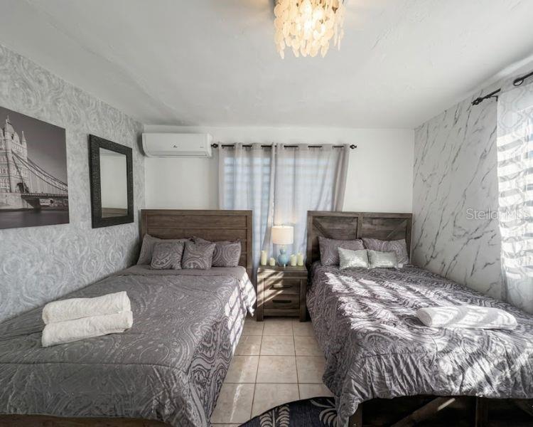 A bedroom features two beds with patterned gray bedding, a nightstand, and textured wallpaper — Carr-10 E BO LOS CAÑOS CARR-10 R651 KM 10.5, ARECIBO, PR