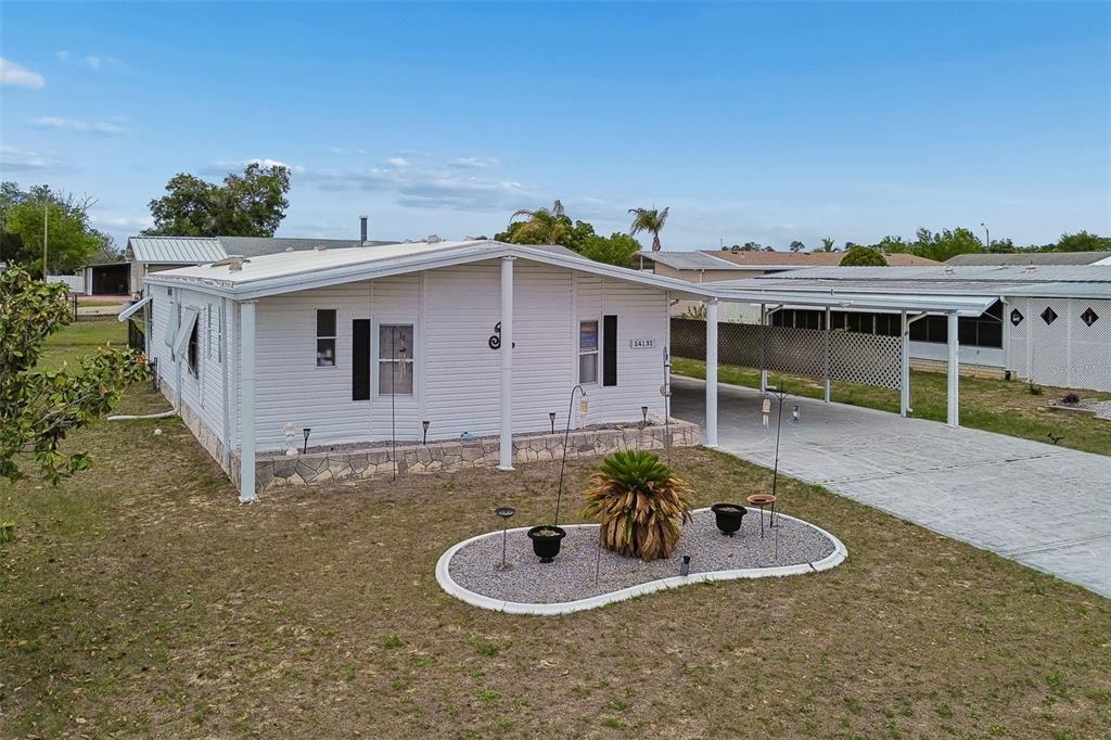 A white manufactured home with a carport and a landscaped front yard — 14131 DELSILVER DRIVE, BROOKSVILLE, FL