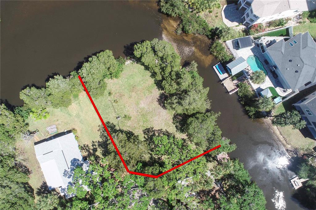 An aerial view shows a vacant waterfront lot outlined in red next to existing homes — 5274 MILLER BAYOU DRIVE, PORT RICHEY, FL