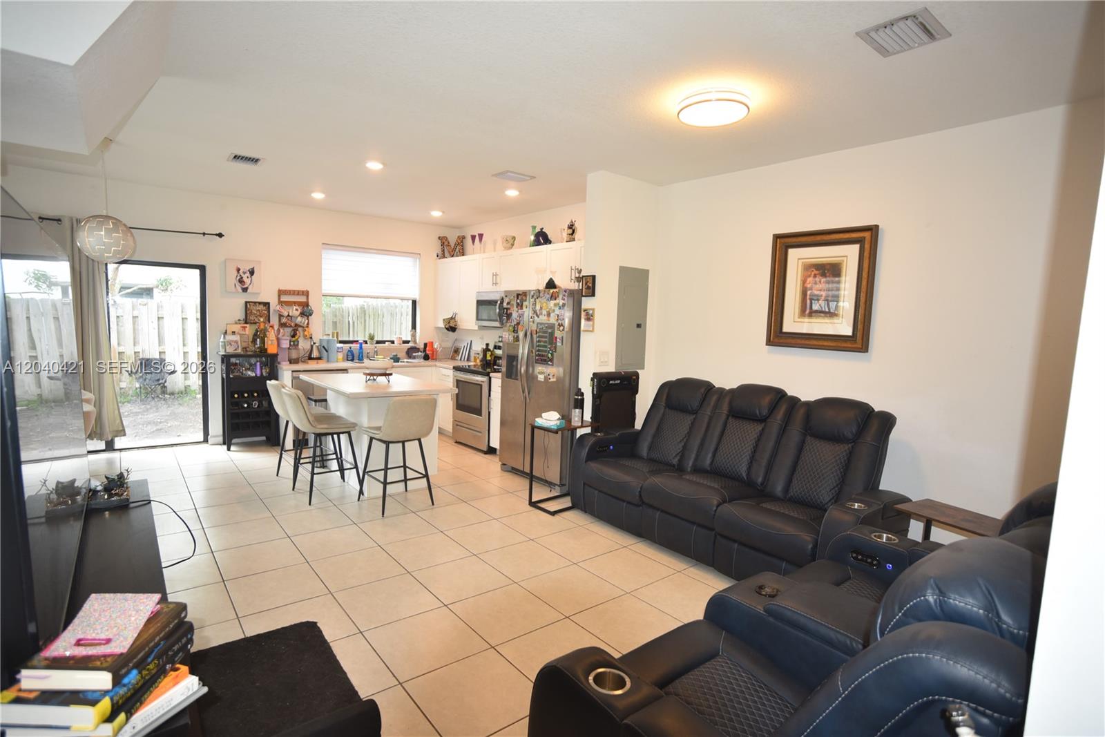 An open-concept kitchen and living area features tile flooring, dark leather seating, and stainless appliances — 21404 NE 3rd Path, Miami FL 33179, MIAMI, FL