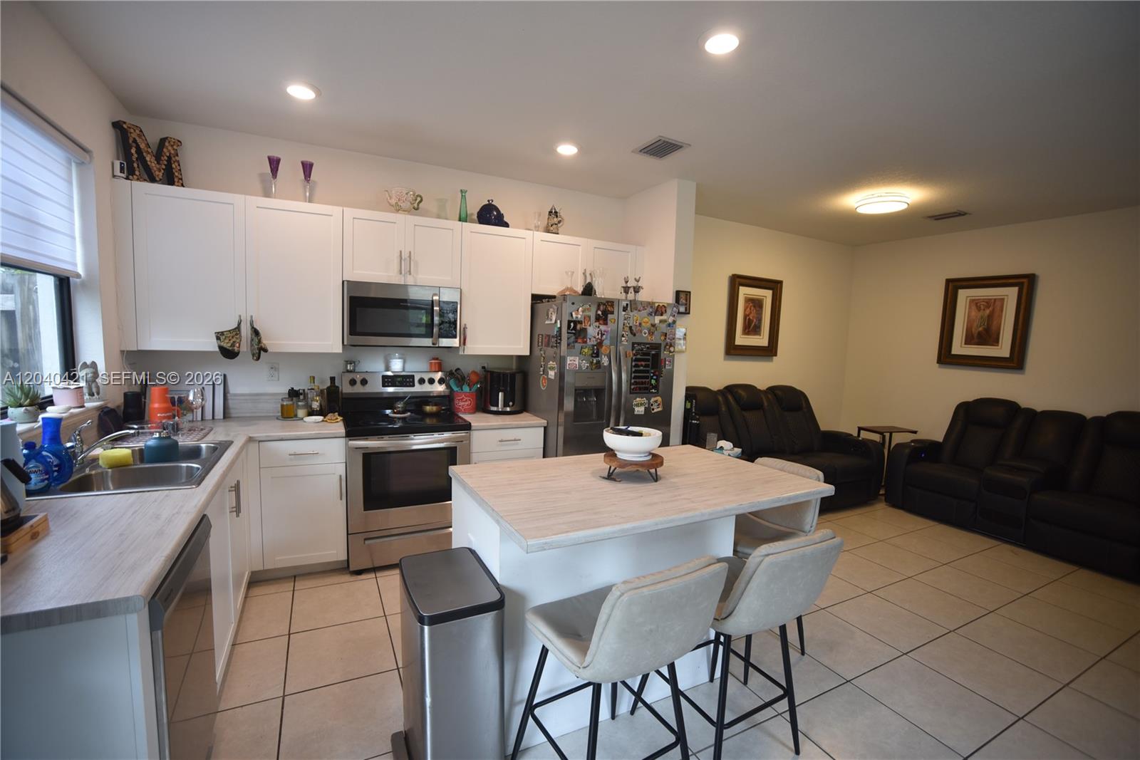 A kitchen with white cabinets and a central island opens into a living area — 21404 NE 3rd Path, Miami FL 33179, MIAMI, FL