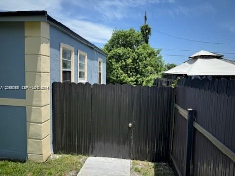 A blue house exterior features a dark privacy fence and a gate leading to a yard — 863 NW 139th St, Miami FL 33168, MIAMI, FL