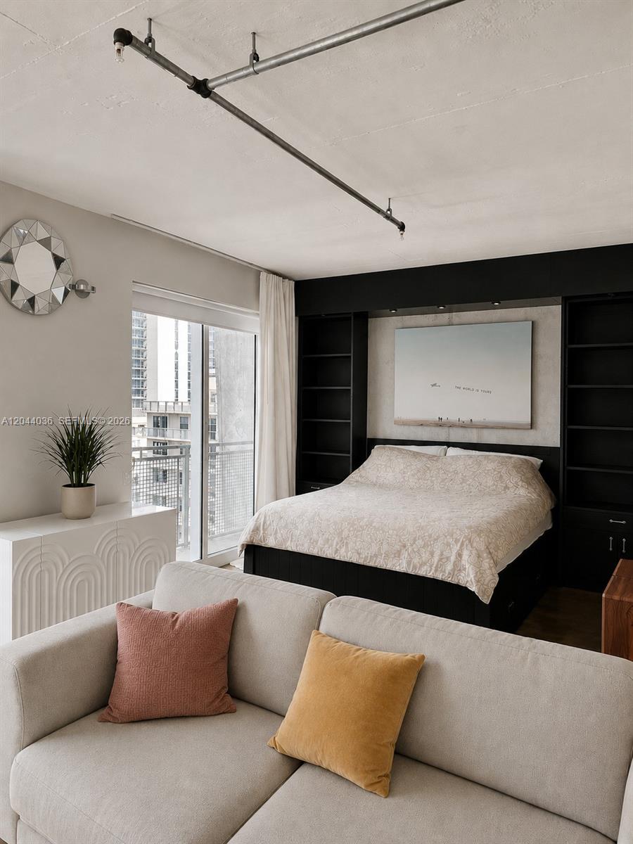 A bedroom features a bed with built-in shelving, a sofa, and an industrial ceiling pipe — 455 NE 25th St # 806, Miami FL 33137, MIAMI, FL
