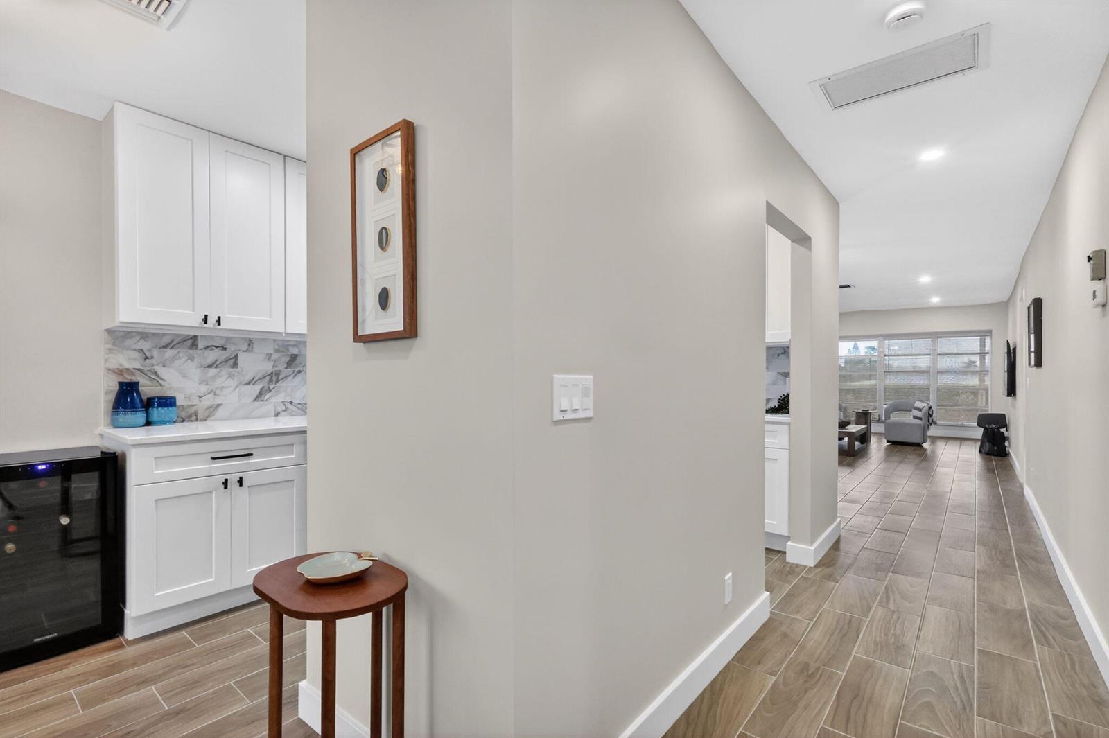 A hallway with wood-look tile floors leads to a living area past a small bar — 1101 Cactus Terrace # 204, Delray Beach FL 33445, DELRAY BEACH, FL