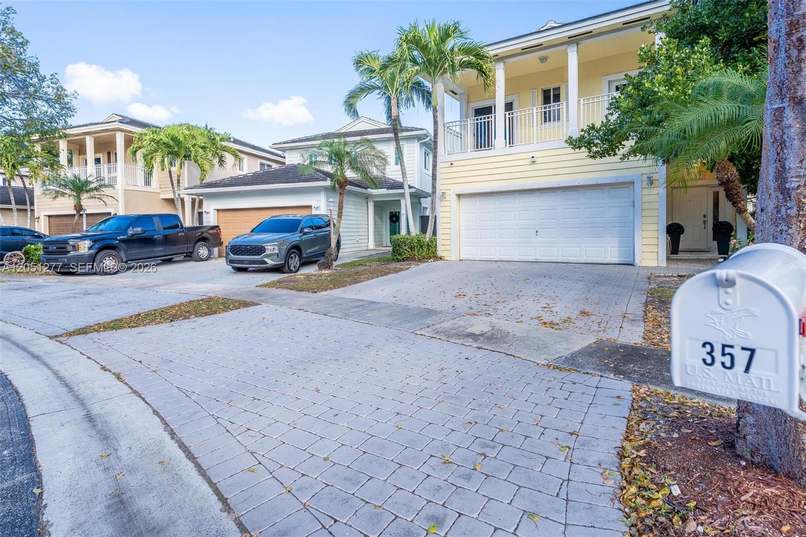 A street-level view shows three multi-story houses with paved driveways and parked vehicles — 357 NE 35th Ter, Homestead FL 33033, HOMESTEAD, FL