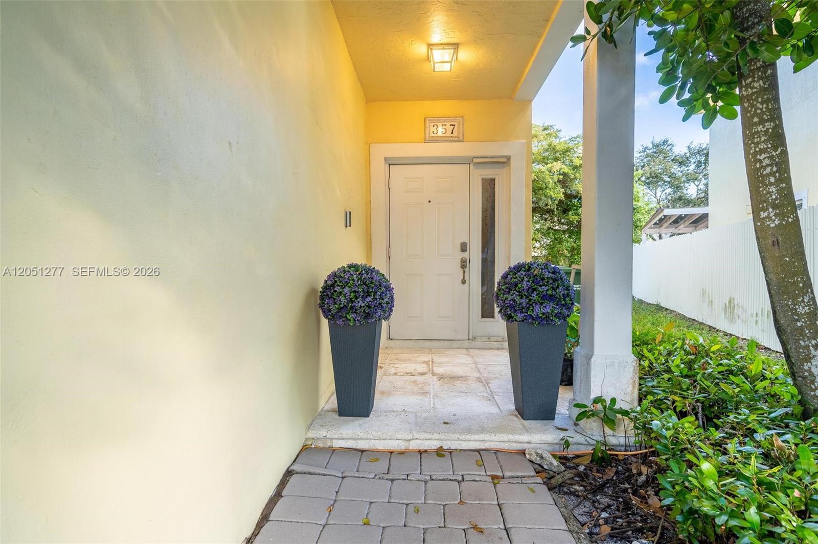 A front entryway features a white door, two potted plants, and a stone walkway — 357 NE 35th Ter, Homestead FL 33033, HOMESTEAD, FL