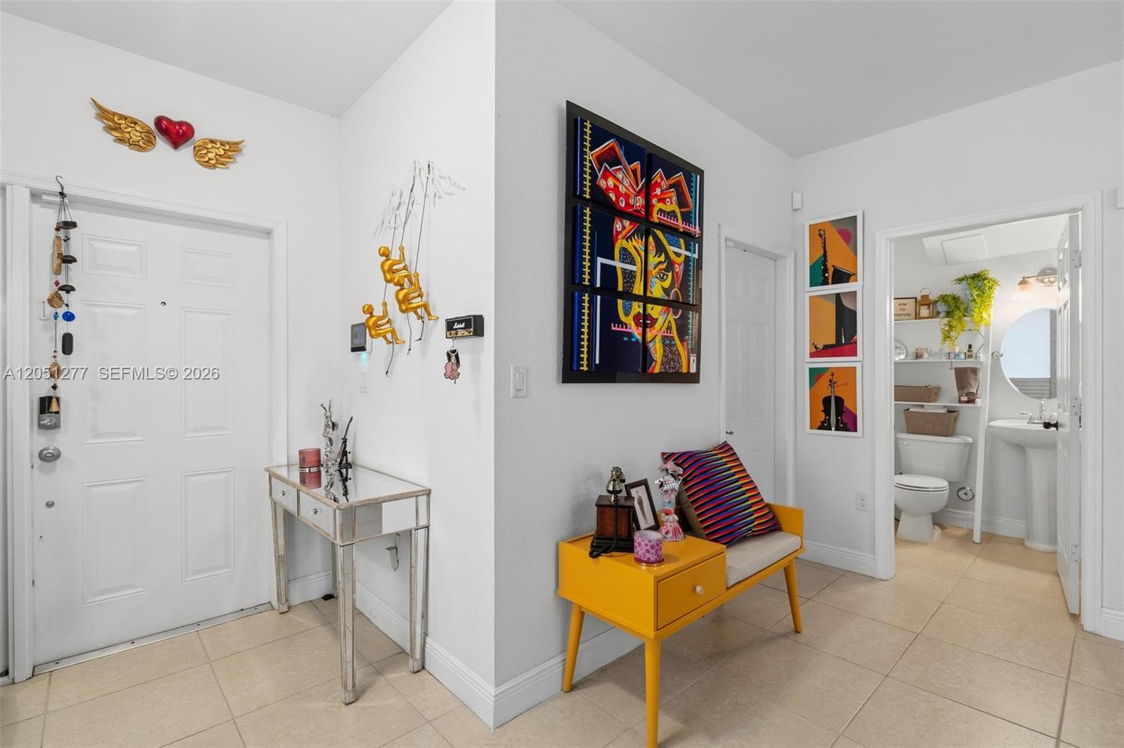 An entryway features a mirrored console table, a yellow bench, and colorful wall art — 357 NE 35th Ter, Homestead FL 33033, HOMESTEAD, FL