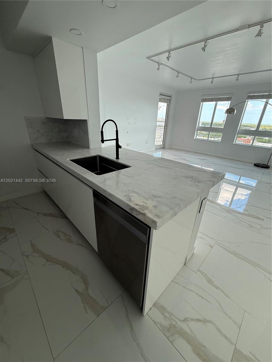A modern kitchen features a marble-topped island, white cabinetry, and light-colored tile flooring — 7350 SW 89th St # 1602S, Miami FL 33156, MIAMI, FL