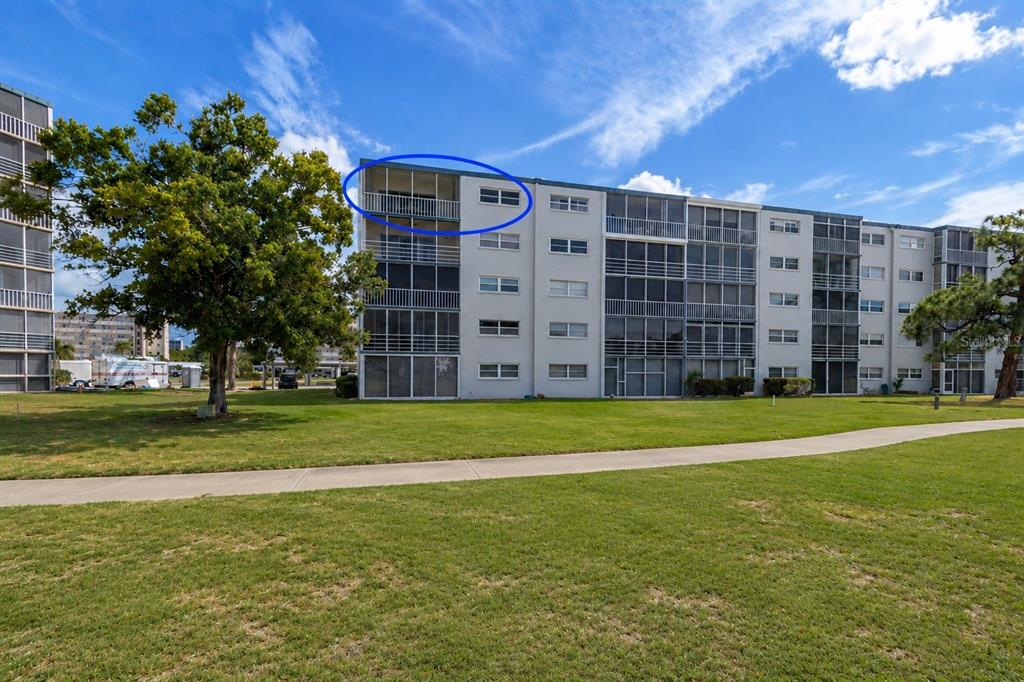 A multi-story apartment building with a blue circle highlighting a top-floor balcony — 3880 IRONWOOD LANE UNIT 508E, BRADENTON, FL