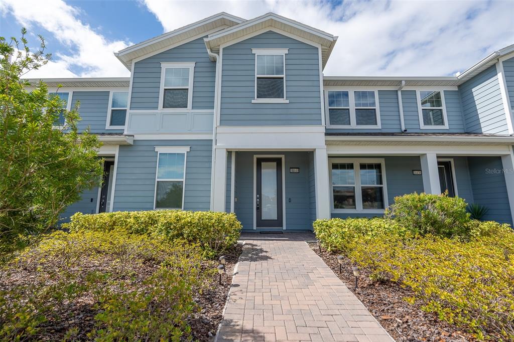 A two-story blue house with a paved walkway leading to a central front entrance — 14440 ORCHID ISLAND DRIVE, ORLANDO, FL