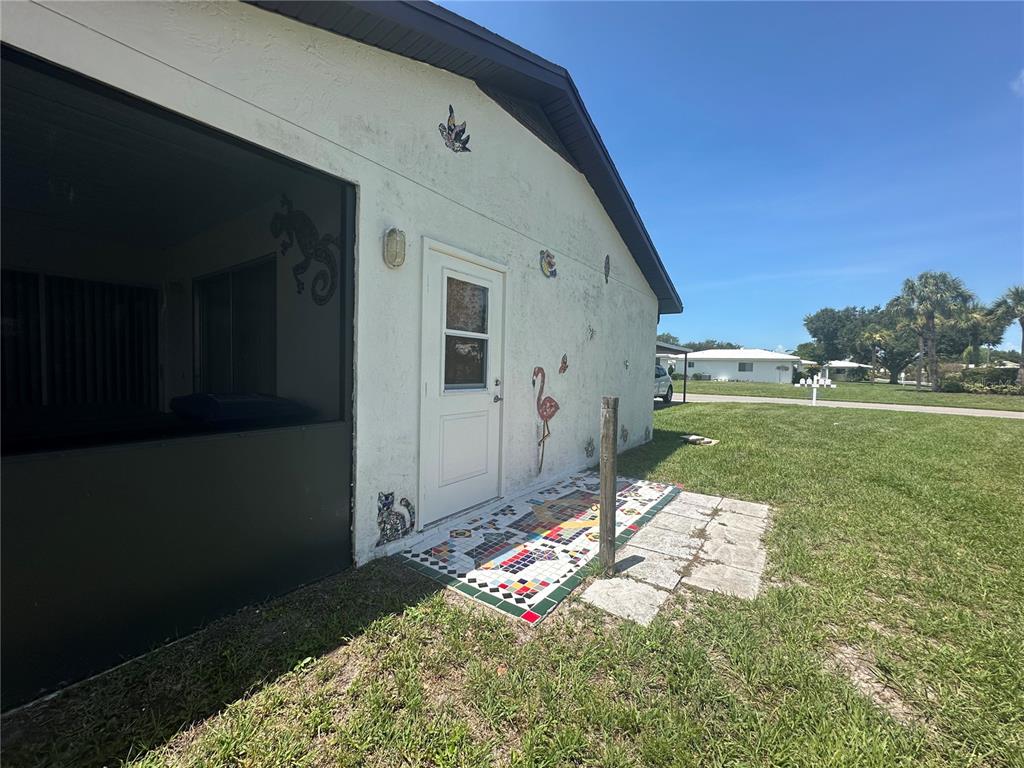 A one-story house with a paved patio, green trim, and a palm tree in front — 166 CIRCLEWOOD DRIVE UNIT 101, VENICE, FL