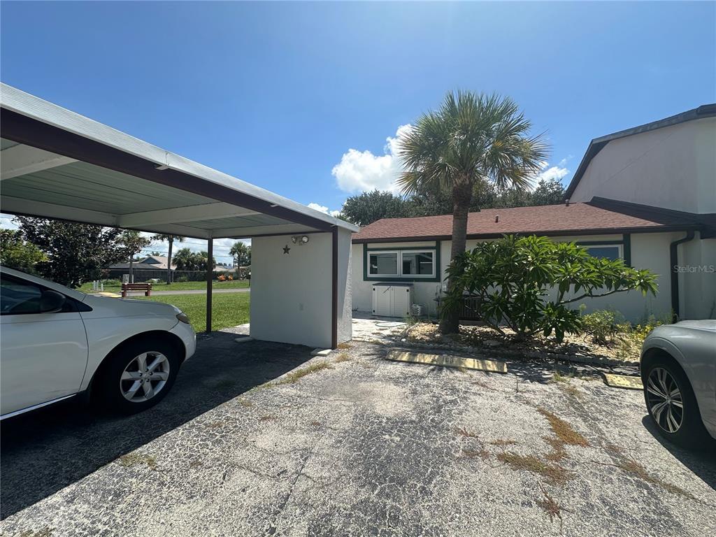 A white house exterior features green trim, a paved patio, and a palm tree — 166 CIRCLEWOOD DRIVE UNIT 101, VENICE, FL