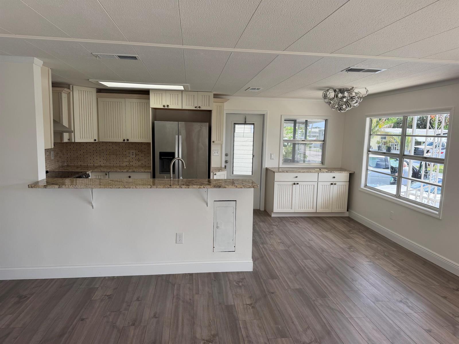 A kitchen with white cabinetry, granite countertops, and wood-look flooring in an open-concept space — 2041 SW 84th Avenue, Davie FL 33324, DAVIE, FL