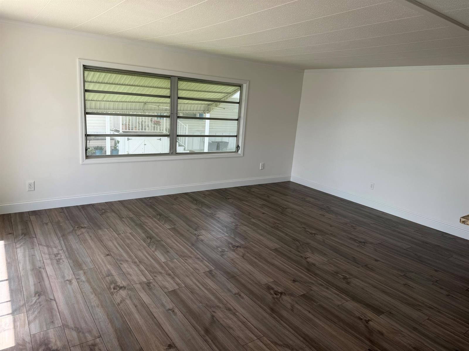 An empty room with white walls, dark wood-look flooring, and a large horizontal window — 2041 SW 84th Avenue, Davie FL 33324, DAVIE, FL