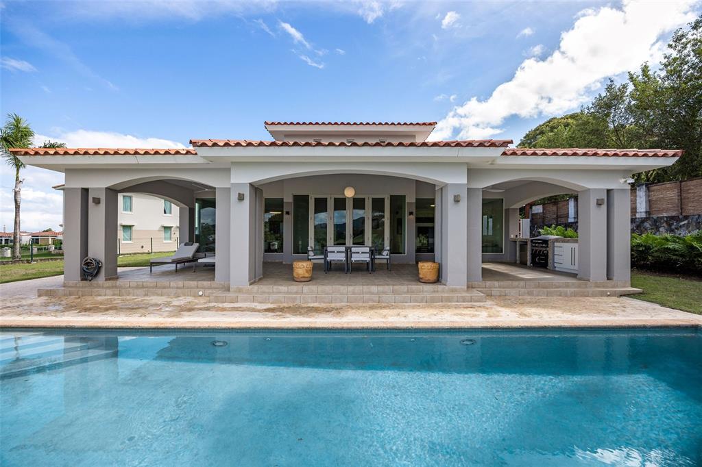 A swimming pool sits in front of a house with a covered patio and columns — #1 LOS LAGOS, HUMACAO, PR