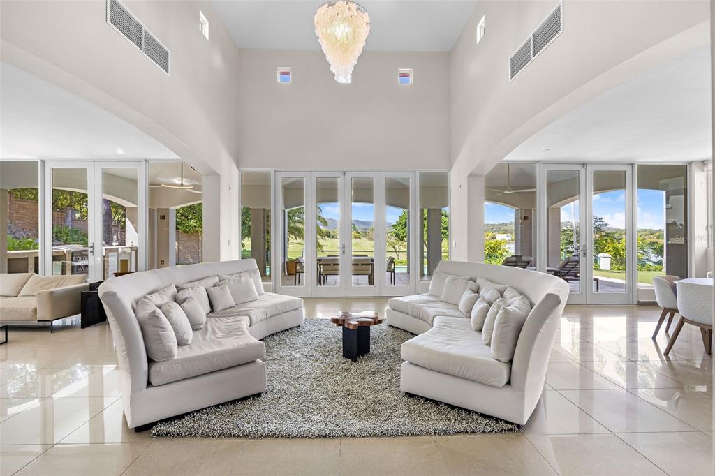 A spacious living room features two curved white sofas, a central rug, and high ceilings — #1 LOS LAGOS, HUMACAO, PR