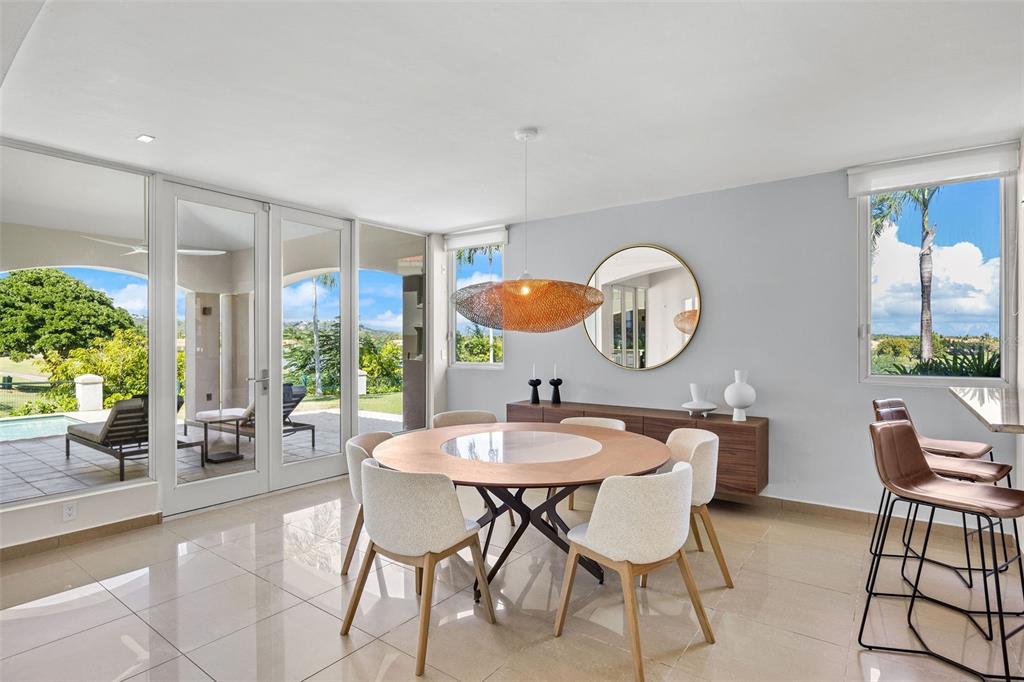 A dining room features a round wooden table, modern chairs, and large glass doors to a patio — #1 LOS LAGOS, HUMACAO, PR