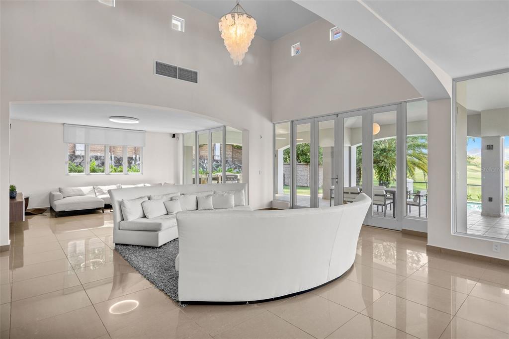 A spacious living room features white curved sofas, tile flooring, and large glass doors — #1 LOS LAGOS, HUMACAO, PR