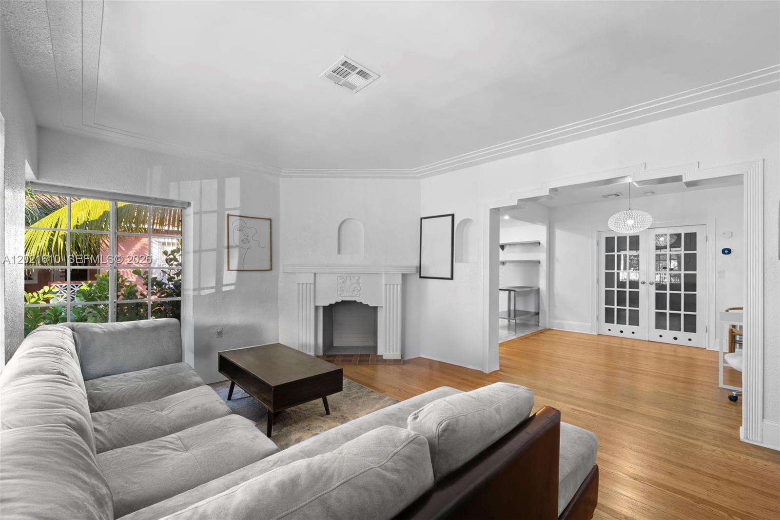 A living room features a fireplace, hardwood floors, a gray sectional, and white walls — 555 NE 73rd St, Miami FL 33138, MIAMI, FL