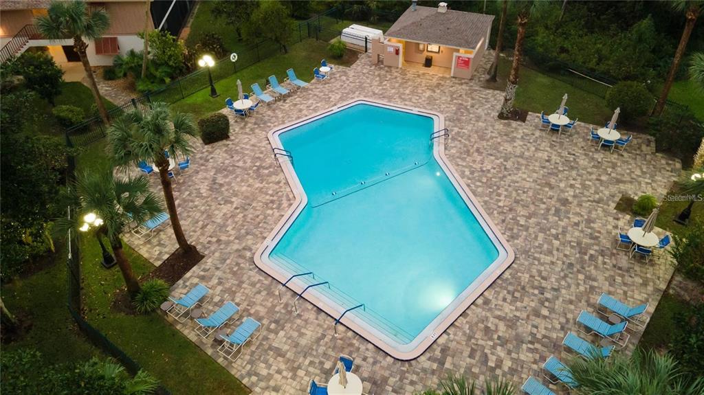 An aerial view shows a swimming pool surrounded by a paved deck and lounge chairs — 100 SWEETGUM WOODS COURT UNIT 8D, DELTONA, FL