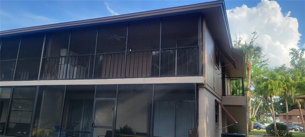 The exterior of a two-story apartment building features screened-in balconies on both levels — 100 SWEETGUM WOODS COURT UNIT 8D, DELTONA, FL