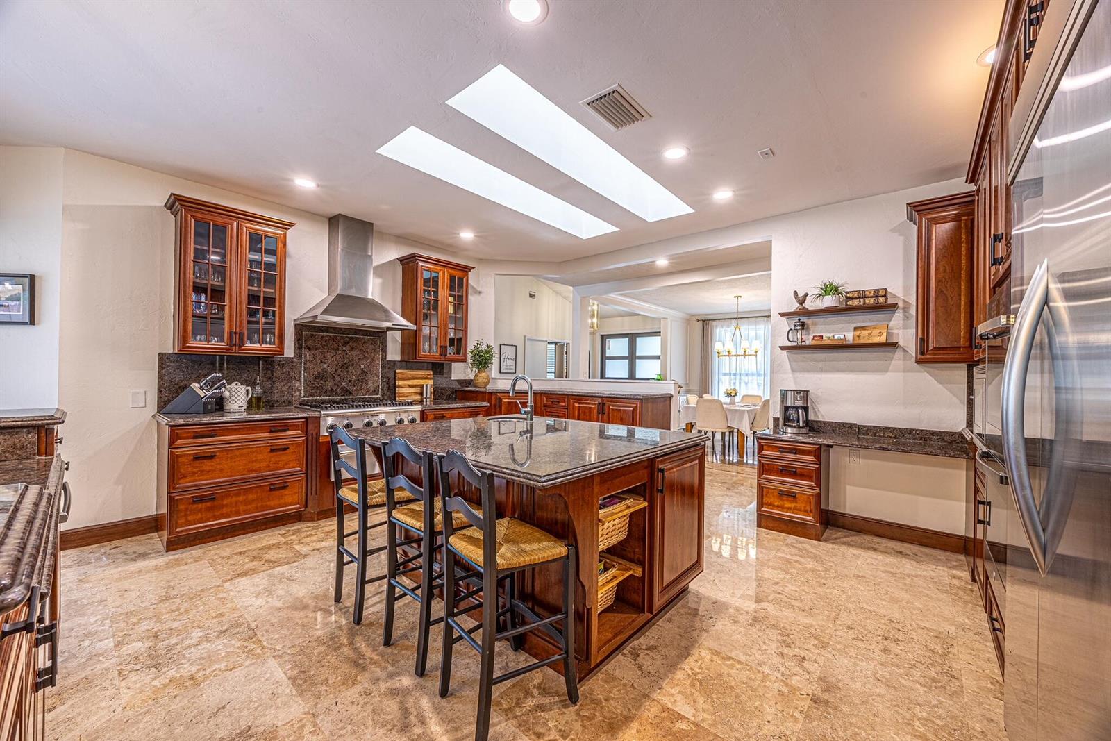 A kitchen features dark wood cabinetry, granite countertops, a central island, and two large skylights — 1985 Parkside Circle S, Boca Raton FL 33486, BOCA RATON, FL