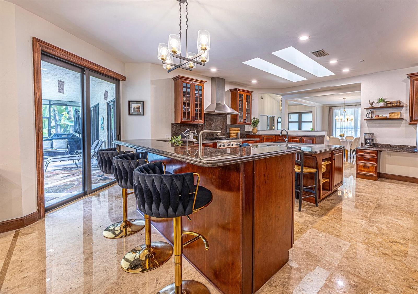 A kitchen with dark wood cabinets, granite countertops, bar stools, and marble flooring — 1985 Parkside Circle S, Boca Raton FL 33486, BOCA RATON, FL