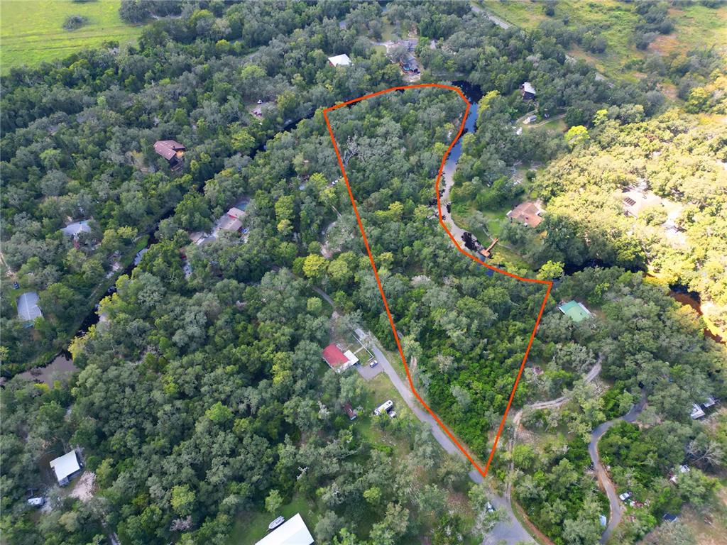 An aerial view shows a wooded lot outlined in orange bordering a narrow waterway — 0012 MARCHMONT CIRCLE, DADE CITY, FL