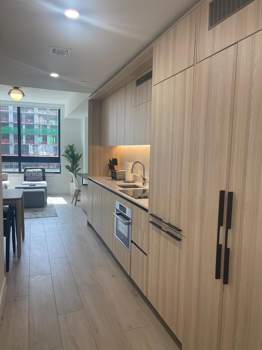 A modern kitchen features light wood cabinetry, stainless steel appliances, and a view of construction — 225 N Miami Ave # 805, Miami FL 33128, MIAMI, FL