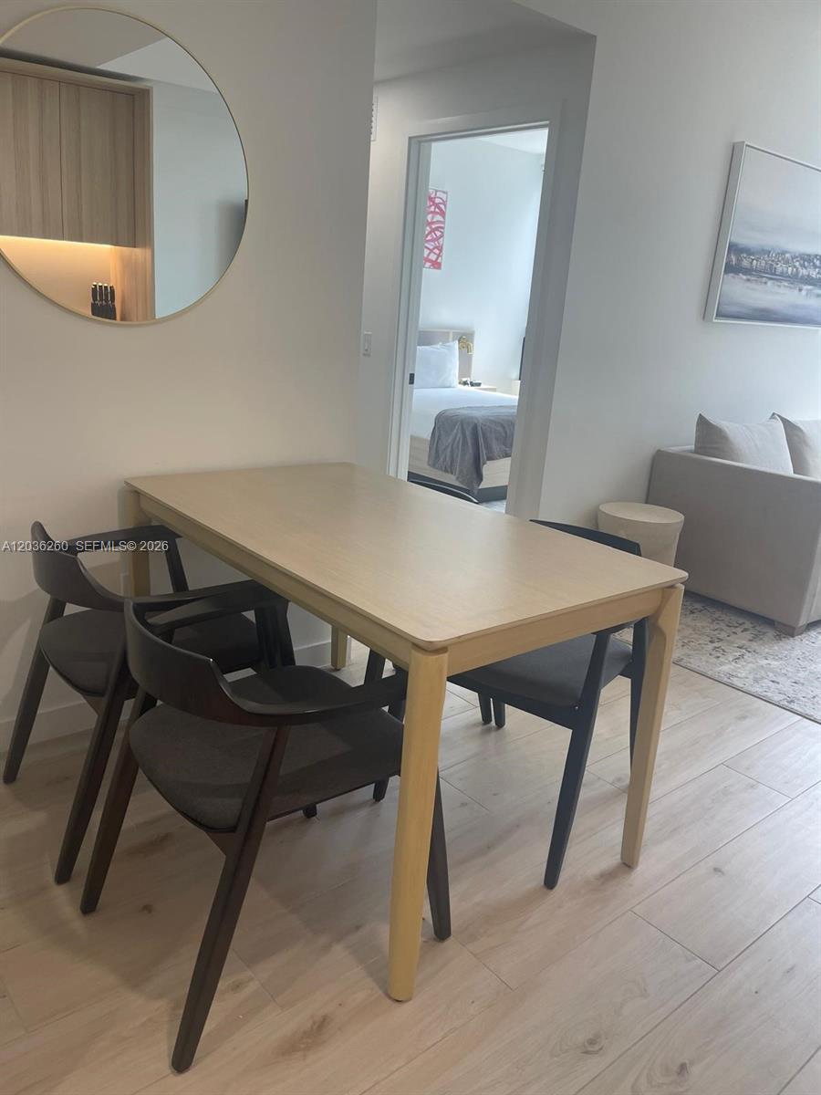 A dining area features a light wood table with dark chairs and a round mirror — 225 N Miami Ave # 805, Miami FL 33128, MIAMI, FL