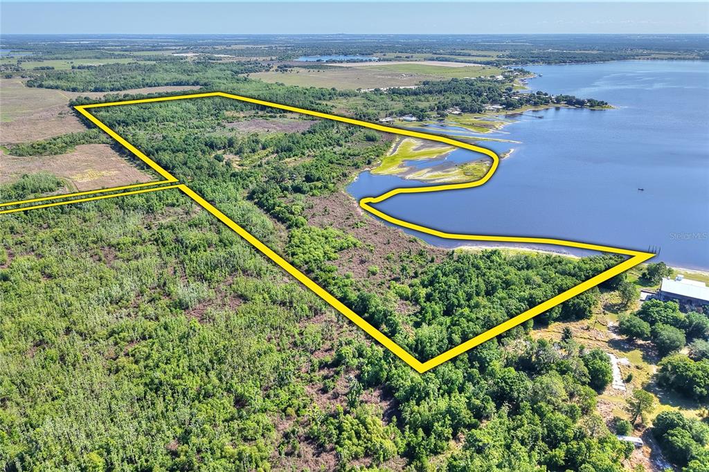 An aerial view shows a large, wooded plot of land outlined in yellow bordering a lake — 0 LAKE BUFFUM ROAD W, FORT MEADE, FL