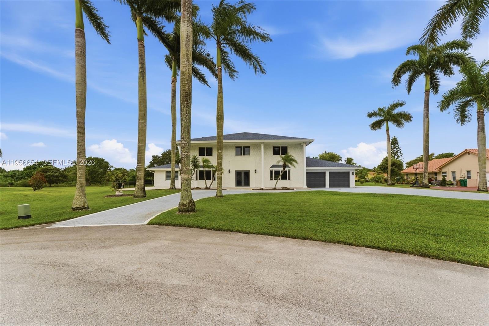 A two-story white house with a paved driveway and palm trees on a grassy lawn — 11824 SW 43rd Ct, Davie FL 33330, DAVIE, FL
