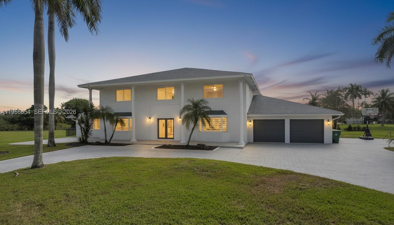 A two-story white brick house features a paved driveway, palm trees, and a two-car garage — 11824 SW 43rd Ct, Davie FL 33330, DAVIE, FL