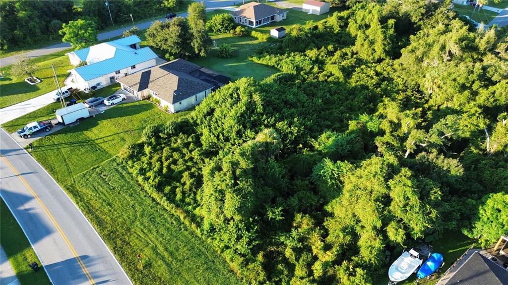 An aerial view shows a residential property with a house, a large wooded lot, and vehicles — S BISCAYNE DRIVE, NORTH PORT, FL