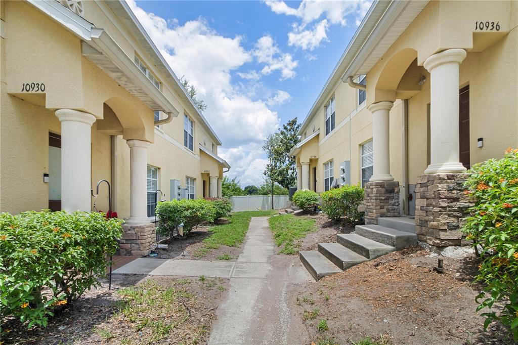 A concrete walkway leads between two beige townhouses with stone-accented columns and front steps — 10932 BRICKSIDE COURT UNIT 10932, RIVERVIEW, FL