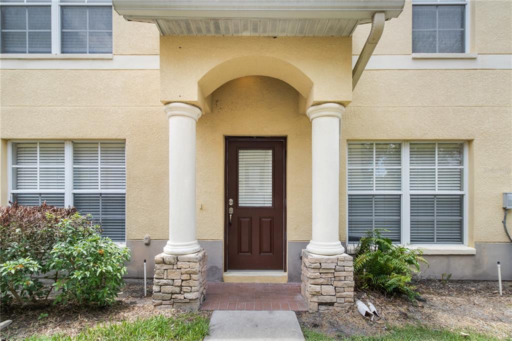 The exterior of a tan building features a covered entryway with two white columns — 10932 BRICKSIDE COURT UNIT 10932, RIVERVIEW, FL