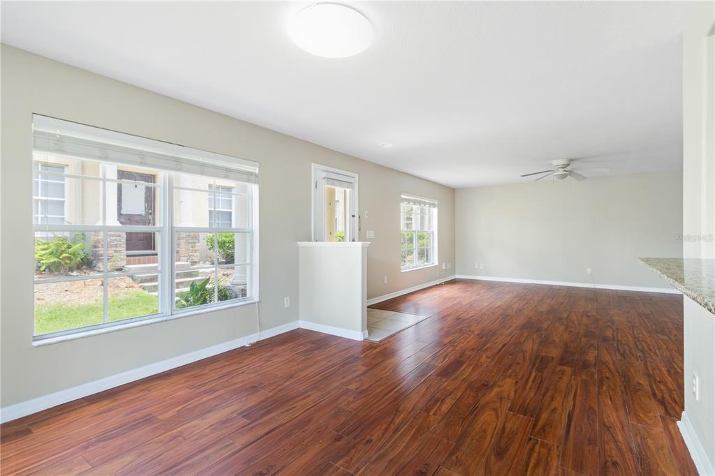 An empty room with wood-look flooring, a ceiling fan, and a large window — 10932 BRICKSIDE COURT UNIT 10932, RIVERVIEW, FL