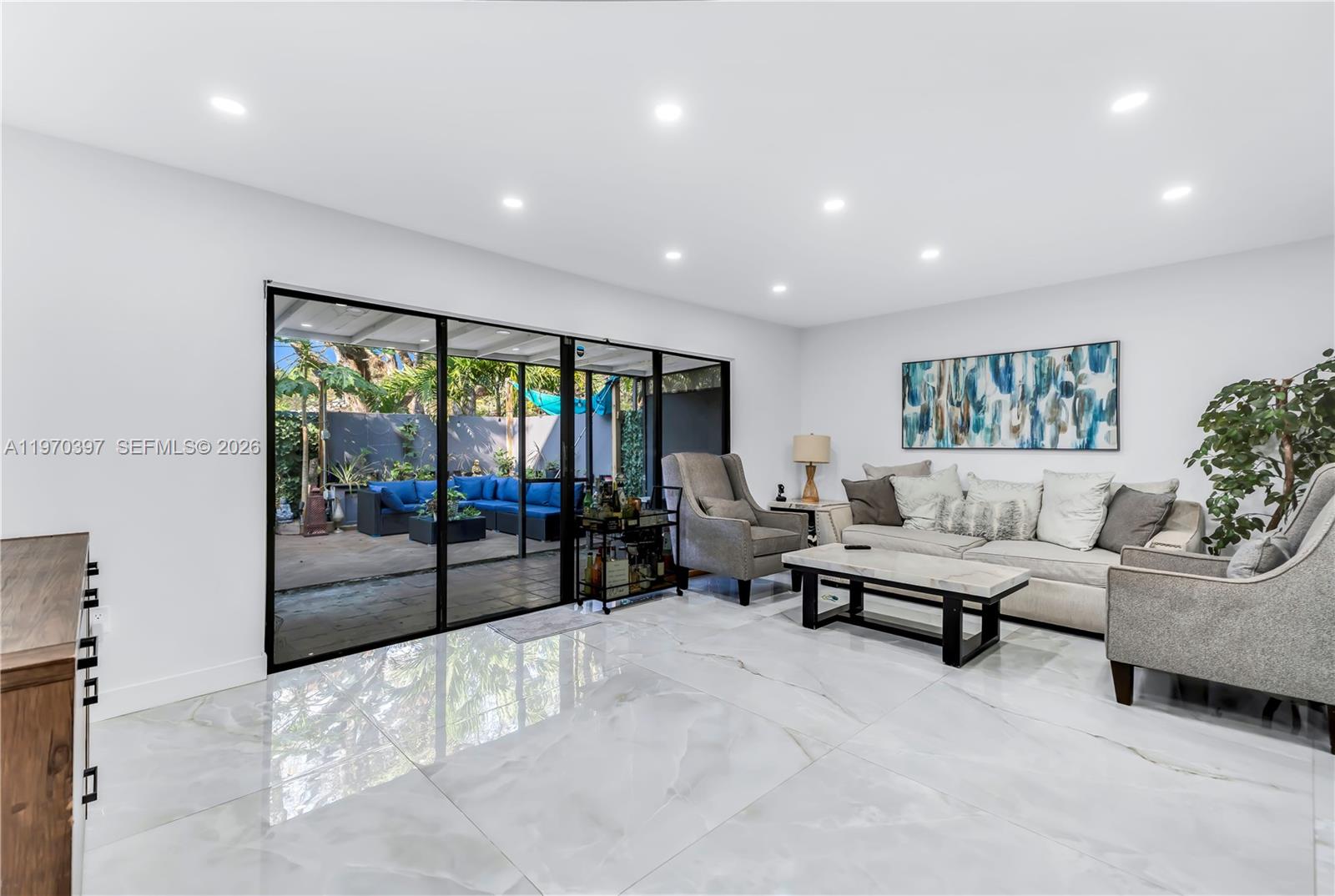 A living room features white marble floors, a sofa, armchairs, and sliding glass doors — 3321 Simms St # 13B, Hollywood FL 33021, HOLLYWOOD, FL