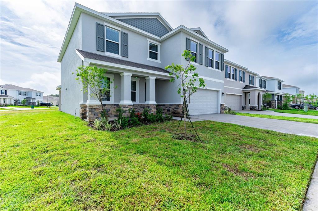A two-story suburban townhouse with a gray exterior, stone accents, and a concrete driveway — 2560 WARREN ACRES BOULEVARD, WESLEY CHAPEL, FL