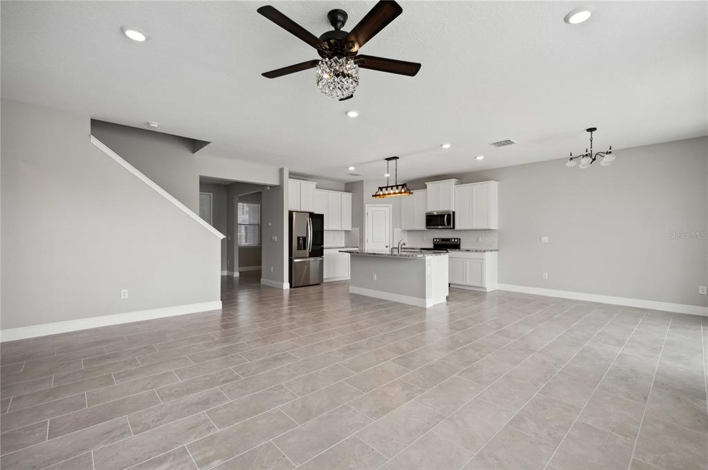 An open-concept kitchen and living area features light gray tile flooring and white cabinetry — 2560 WARREN ACRES BOULEVARD, WESLEY CHAPEL, FL