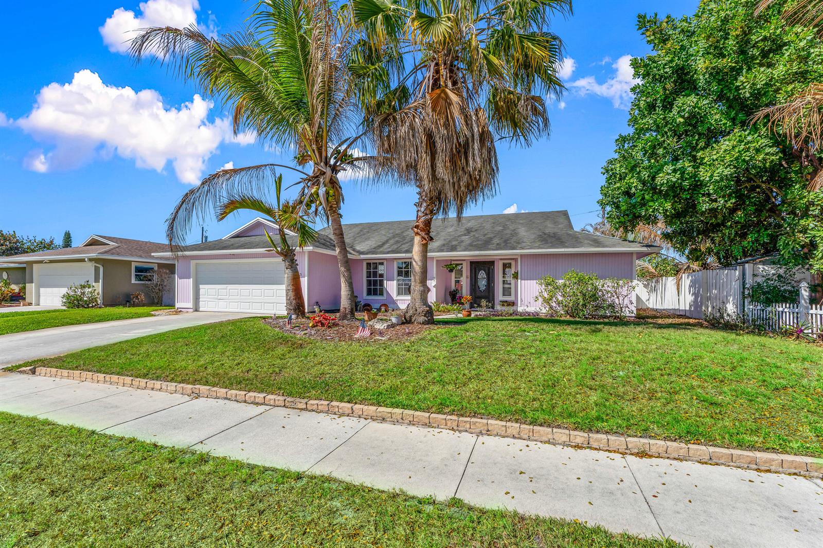 A single-story pink house with a two-car garage and palm trees in the front yard — 4153 Russell Street, Jupiter FL 33469, JUPITER, FL