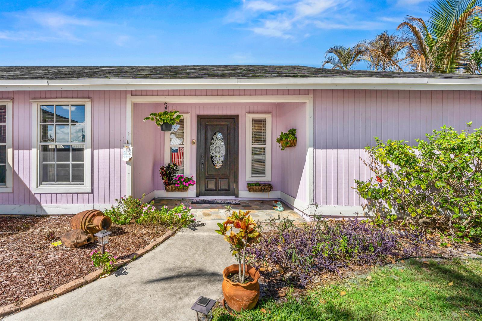The exterior of a light pink house features a dark front door and a concrete walkway — 4153 Russell Street, Jupiter FL 33469, JUPITER, FL