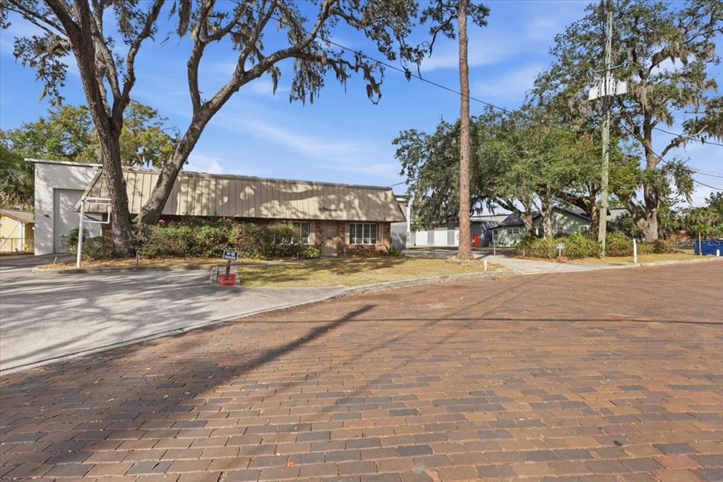 A low-slung commercial building with a metal awning sits behind a brick-paved street — 1022 WILFRED DRIVE, ORLANDO, FL